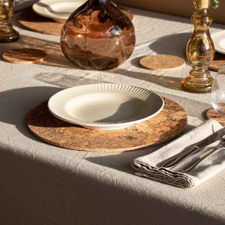 natural cork placemat and coaster laid out on a table with a plate and cutlery